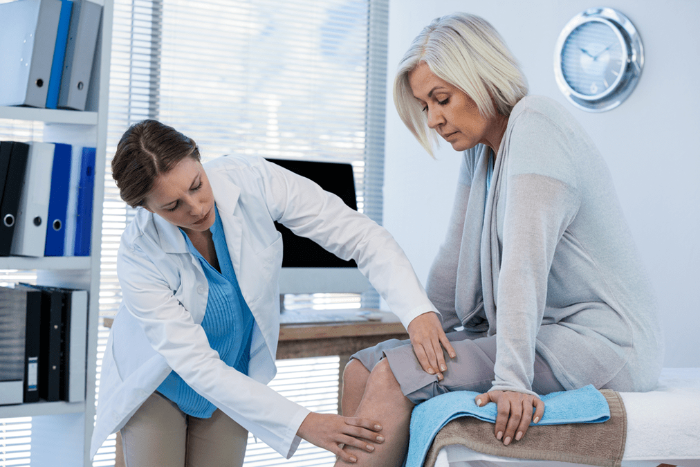 Lekarz bada pacjenta z artrozą stawu kolanowego